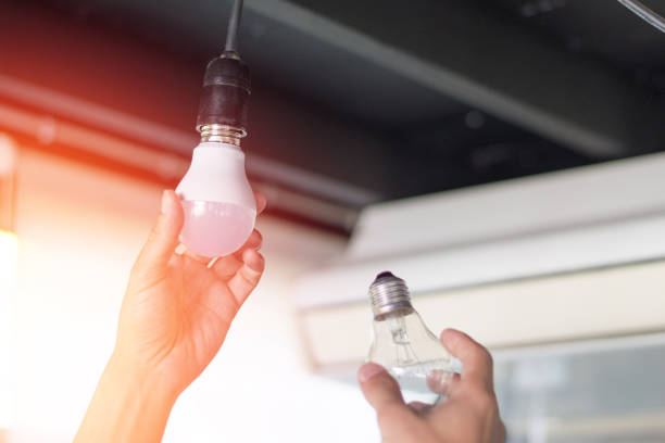 Power saving concept. Asia man changing compact-fluorescent (CFL) bulbs with new LED light bulb. Power saving concept. Asia man changing compact-fluorescent (CFL) bulbs with new LED light bulb. energy efficient lightbulb stock pictures, royalty-free photos & images