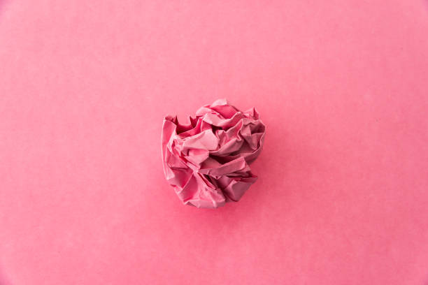 istock Pink crumpled paper ball on pink background 1058203012