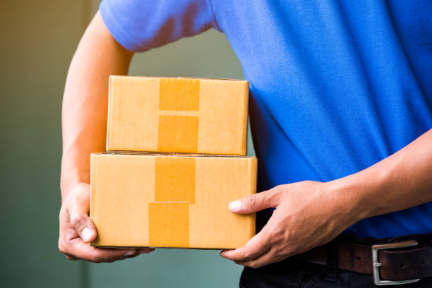 istock Close up Delivery man in blue uniforms holding parcel cardboard box. 1058203414