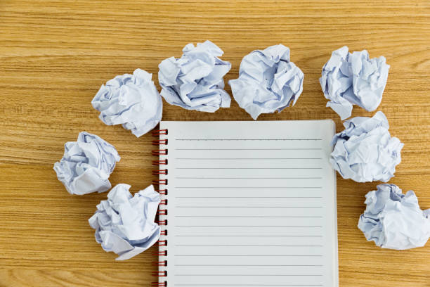 istock Note pad and crumpled paper balls on wooden table 1058203712
