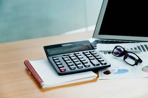 Photo of Calculator, laptop and other office supply on desk