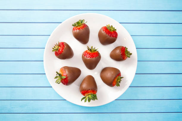 fragole ricoperte di cioccolato su un tavolo di legno blu - chocolate dipped foto e immagini stock