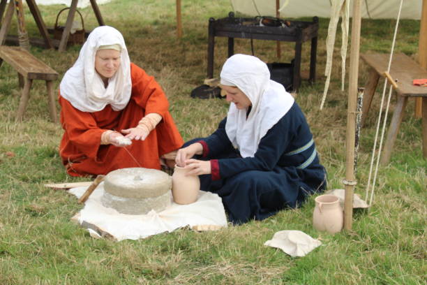 Flour Making Demonstration Battle, UK - 14 October, 2018: Woman in saxon period clothing demonstrating how to make flour using mill stones at a Battle of Hastings reenactment weekend. anglo saxon photos stock pictures, royalty-free photos & images