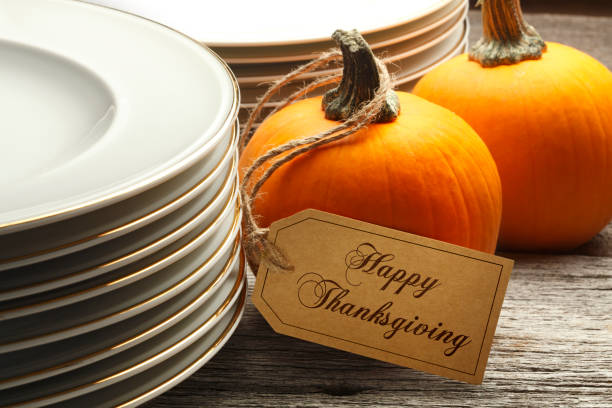 istock Happy Thanksgiving Tag Hanging From A Pumpkin Next To Stack Of Plates 1058214694
