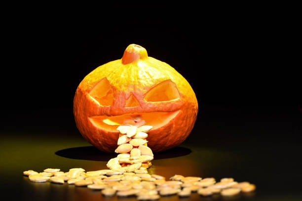 istock Halloween pumpkin and pumpkin seeds isolated on a black background with yellow backlight 1058214812