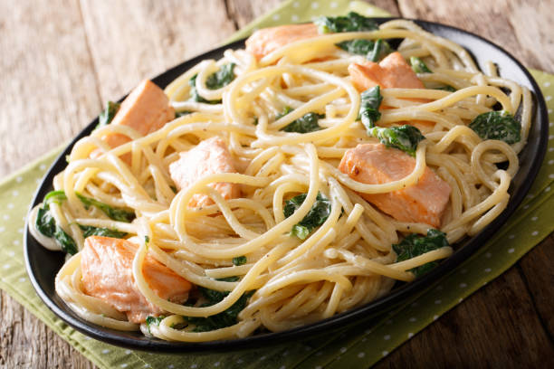 istock Italian cuisine: spaghetti with salmon, cream cheese and spinach close-up on plate. horizontal 1058216296
