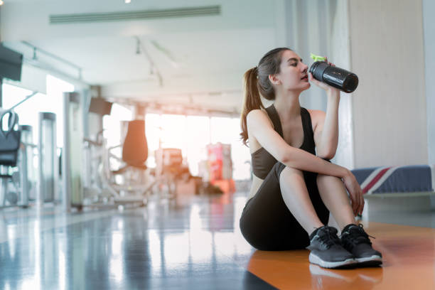 entrenamiento de ejercicio de mujer en la última hora de fitness gimnasio relajarse beber botella de batido de proteína después de culturismo en entrenamiento deporte estilo de vida saludable, - aerobics beautiful bottle body fotografías e imágenes de stock