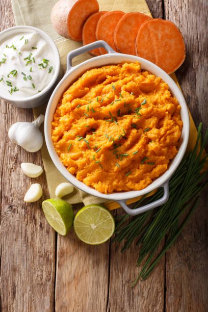 istock Freshly prepared mashed sweet potatoes with herbs, garlic and lime close up in a pot. Vertical top view 1058224934