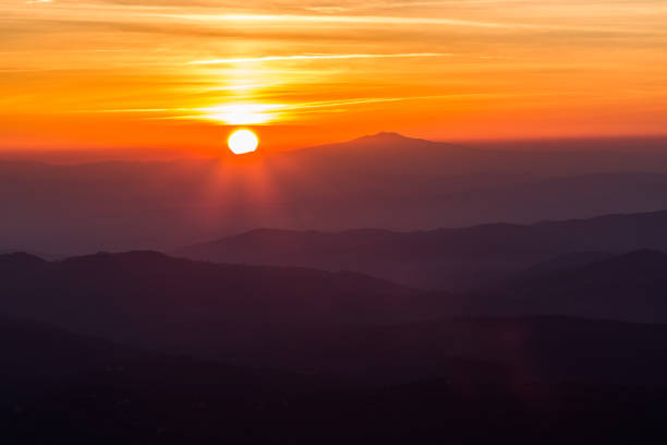 istock Beautiful sunset with sun coming down behind various layers of mountains 1058232922