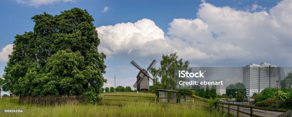 From village to city: Wind mill and "Plattenbau" skyscrapers in Berlin-Marzahn The post mill is a reconstruction of the original 19th century building and is used as a wedding location - Panorama from 3 pictures - additional keywords: nature in the city Berlin Stock Photo