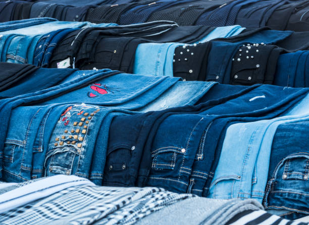 A vibrant collection of neatly folded denim jeans lines a retail table, showcasing various shades of blue and gray. Shoppers can explore these stylish options for their wardrobe.