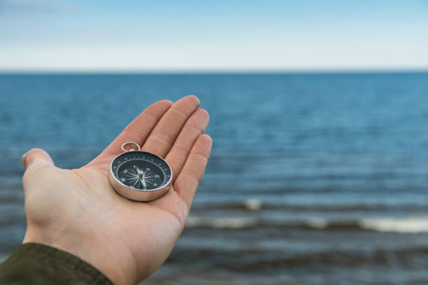 istock Traveler holding compass against blue water 1058248094