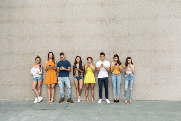 istock Young adults leaning back on wall and social networking 1058258652