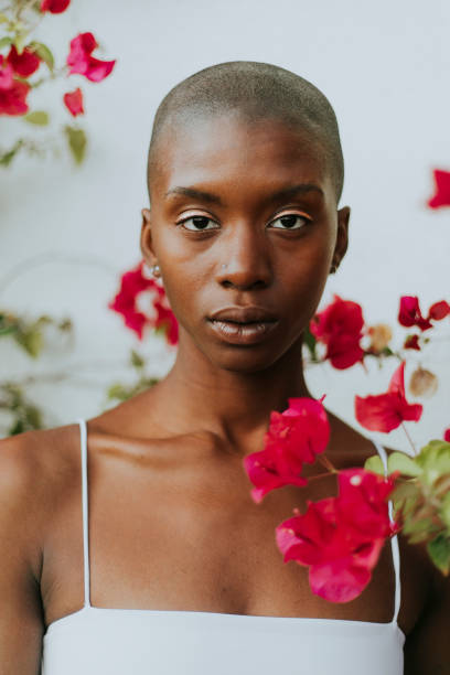 Skinhead woman surrounded by red flowers Skinhead woman surrounded by red flowers skinhead haircut stock pictures, royalty-free photos & images