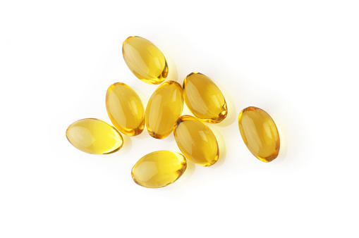 Pile of capsules with cod liver oil close-up isolated on white background. Top view point.