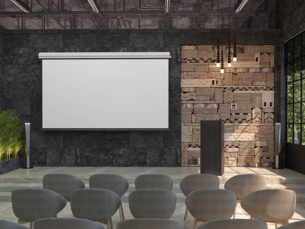 a meeting room with blank white screen for the projector on the black wall. the interior of the conference hall with a stage and a stand for performances. - school hall imagens e fotografias de stock
