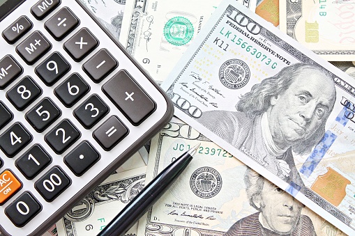 Vista superior o lay flat de calculadora y bolígrafo en dinero en efectivo de dólares americanos photo