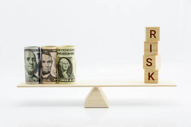 istock Financial, economic risk and risk perception, decision making concept : Dollar bills, risk wood blocks on a basic balance scale, depicts an uncertain event or condition that has an effect on objective 1058274508