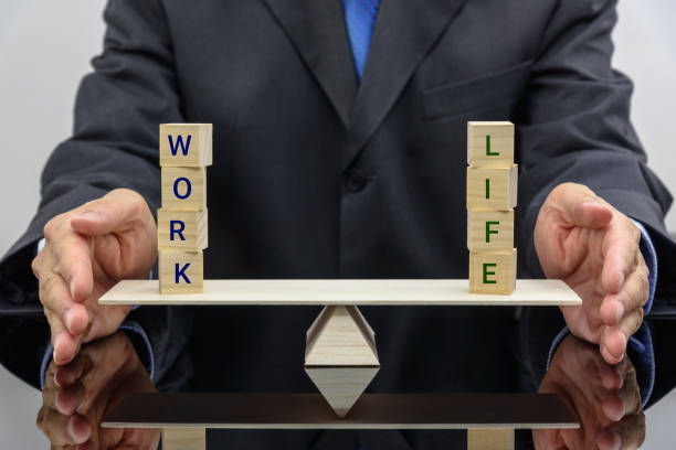 Work life balance concept : Businessman uses his hand protects 2 words on a seesaw or basic balance scale, depicts the balancing between time allocated for work and other aspect of life e.g family etc concepto de equilibrio de la vida de trabajo: aplicaciones de empresario su mano protege 2 palabras en un balancín o en escala de equilibrio básico, representa el equilibrio entre el tiempo asignado para el trabajo y otros aspecto de la familia etcetera