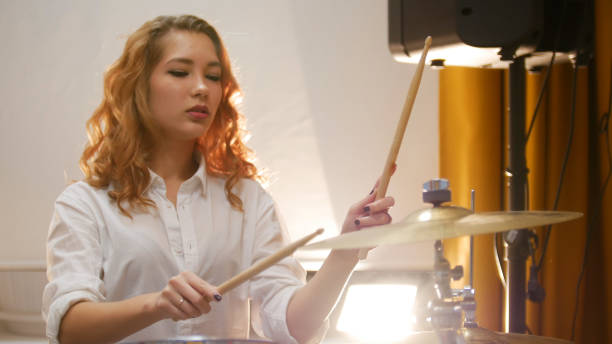 istock Pretty redhead girl playing drums in studio 1058274674