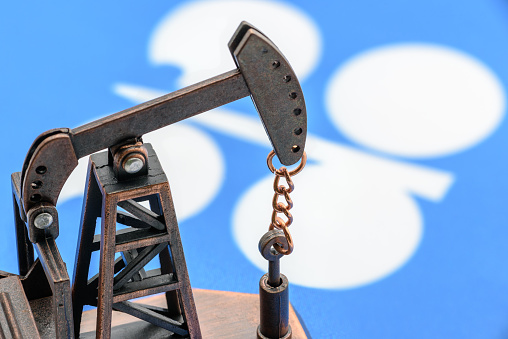 Concepto de petróleo, petrodólar y crudo: bomba jack y bandera de la OPEP u organización de aceite de países exportadores de petróleo, representa la inversión en el desarrollo o producción de la industria petrolera mundial photo