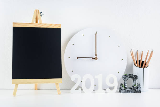2019 happy new year theme, professional designer office concept : Business work space / modern workplace and supplies place on desk table e.g number 2019 white wood cut, chalkboard, pencil, wall clock