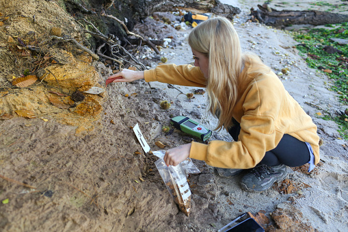 Carrera geología estudiante tomando muestras de rocas costeras y el uso de un GPS para el punto de perno cambia su posición en el sur de Inglaterra como parte de su tesis de Geología de último año sobre el nivel del mar en el Reino Unido photo