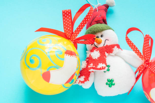 Snowman and a yellow Christmas ball over a beautiful blue Background