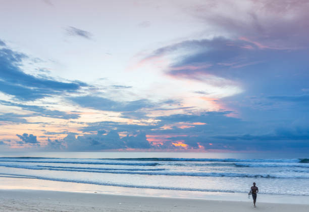 istock A man is standing with a surf in his hands on the sea shore. 1058281694