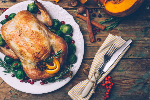 istock Thanksgiving roasted chicken with Brussels sprouts and spices on a rustic wooden table. Thanksgiving dinner or fall dinner concept background with autumn leaves. Thanksgiving table setting background. 1058284910