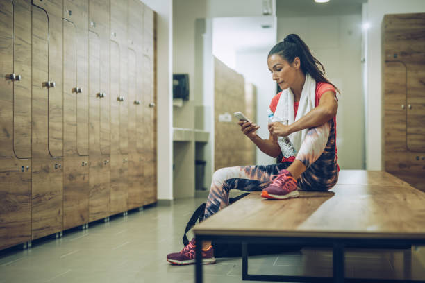 istock Female athlete using cell phone at gym's dressing room. 1058285010