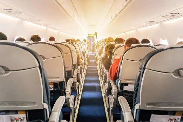 Photo of Commercial aircraft cabin with rows of seats down the aisle