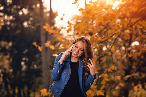 istock Cute girl using cellphone in park with autumn colors. 1058285892
