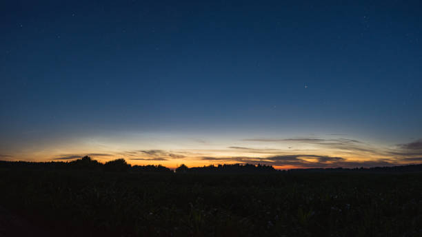 istock Silvery clouds in the sky above the field at night 1058289330