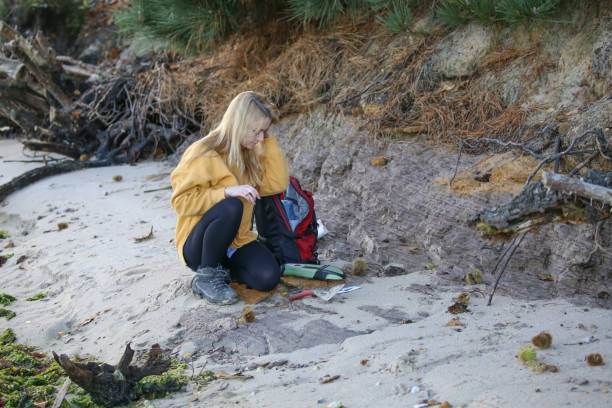 Final year female Geology student taking coastal rock samples and using a GPS to pin point her position in the South of England as part of her final year Geology dissertation on sea level changes in the UK