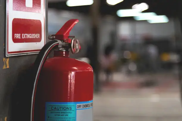 Photo of closeup red fire extinguisher with soft-focus and over light in the background