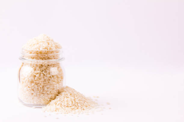 istock Raw round rice in a glass jar, on white background 1058294514