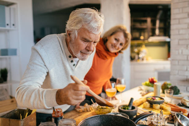 tasting the food they've prepared - cooking senior adult healthy lifestyle couple imagens e fotografias de stock