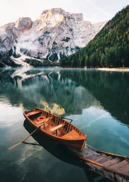 Boats and slip construction in Braies lake with crystal water in background of Seekofel mountain, Dolomites in morning, Italy Pragser Wildsee