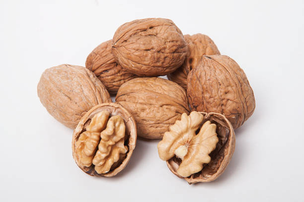 istock Whole unpeeled and broken walnuts on white and wooden background. 1058309200