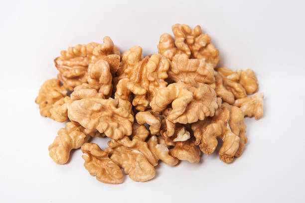 istock Whole unpeeled and broken walnuts on white and wooden background. 1058309572