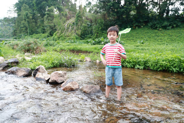 istock Child playing by a stream fishing 1058312820