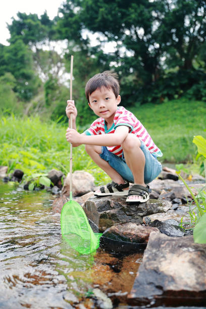 istock Child playing by a stream fishing 1058313420