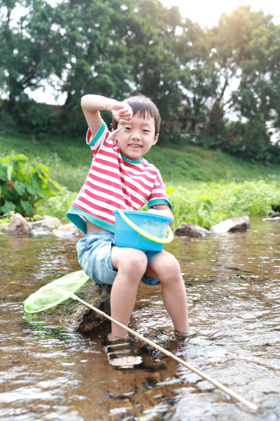 istock Child playing by a stream fishing 1058313466