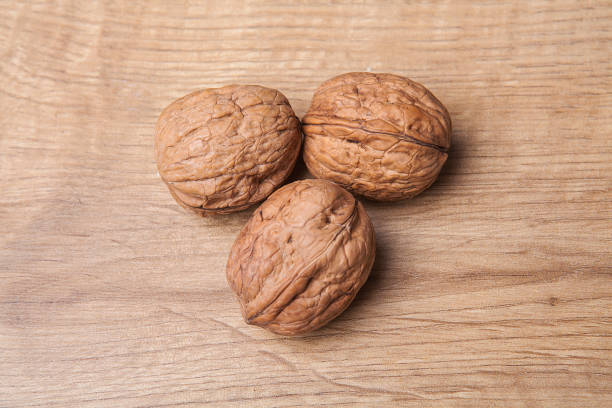 istock Whole unpeeled and broken walnuts on white and wooden background. 1058315748