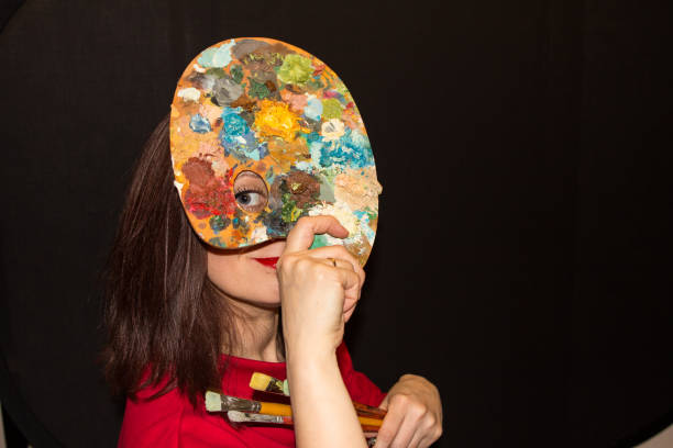 istock pretty young woman holding a palette and looking through it's hole. 1058320696