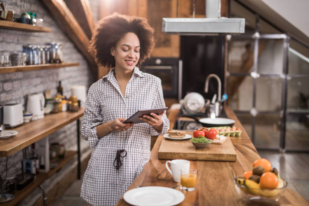 istock Happy African American woman using digital tablet in the kitchen. 1058326530