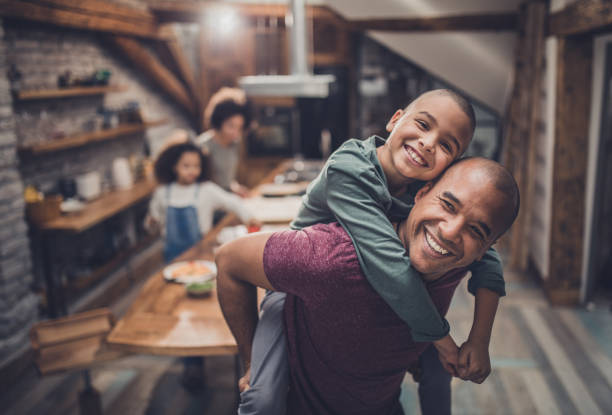 istock Carefree black father having fun while piggybacking his son at home. 1058327510