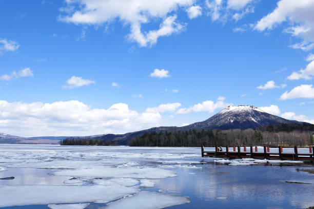 Early spring Lake Akan with ice In winter, Lake Akan is covered with ice. In early spring, it melt and they begin preparation for the sightseeing boat. Mountain behind still keeps snow. national park akan stock pictures, royalty-free photos & images
