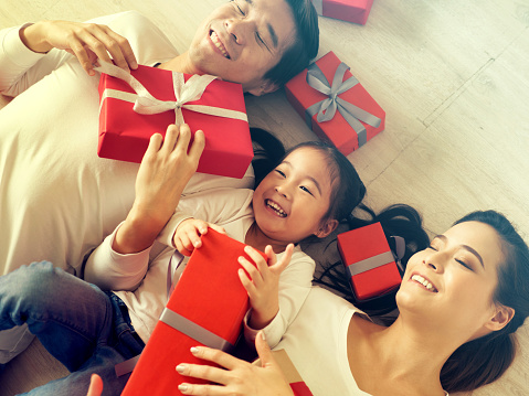 Happy Asian family with giftboxes lying on the floor